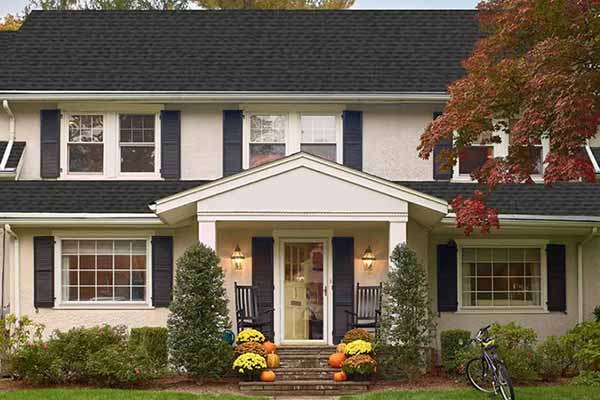 Front view of a beige two-story and mid-class home with black GAF shingles on its roof